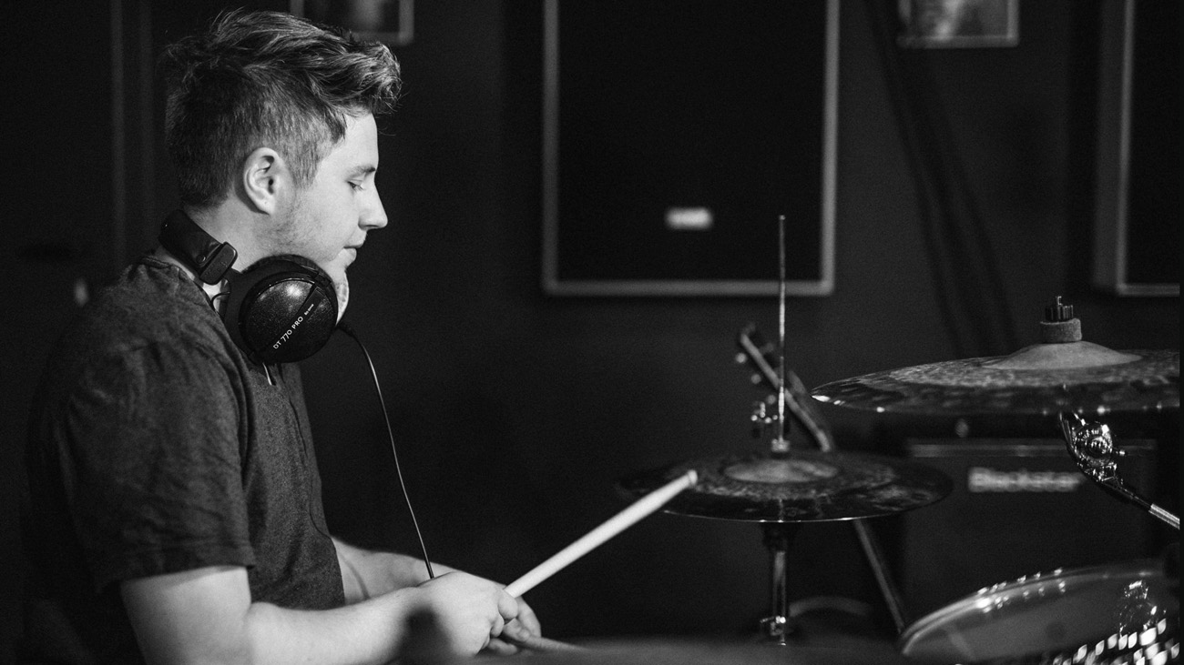 A man playing music with DT-770 PRO 250 Ohms Studio Over-Ear Headphones around his neck