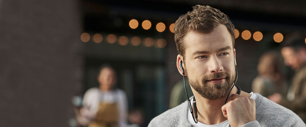 A man with beard pressing buttons on the neckband
