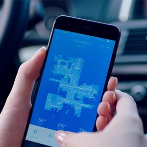 A hand tapping a smartphone, with the phone screen showing a room map