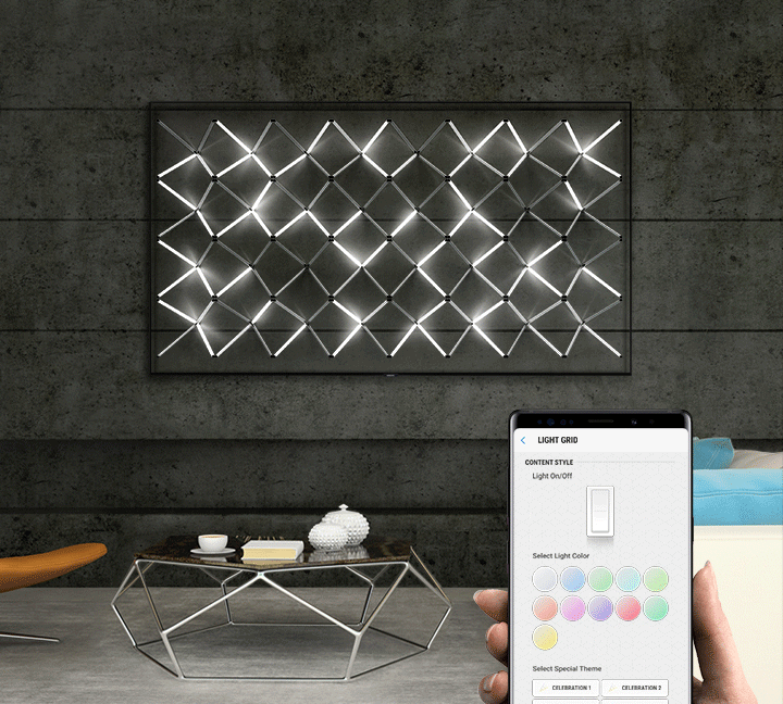 SAMSUNG Q80R display mounted on a wall, with its art installation on screen changing colors by way of a smartphone app being used by a hand