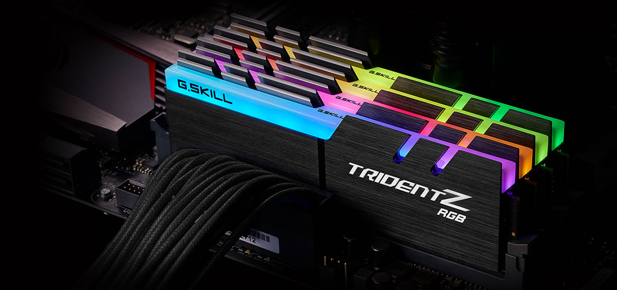 Top front view of four Trident Z modules on a motherboard, all facing slightly to the left, with each module glowing different colors on the RGB strip