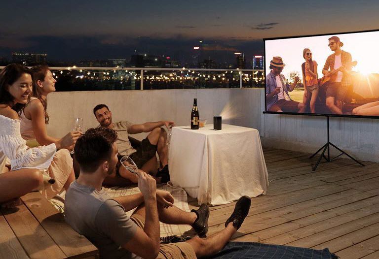 two men and two women watching a show on Nebula Apollo projector on the rooftop