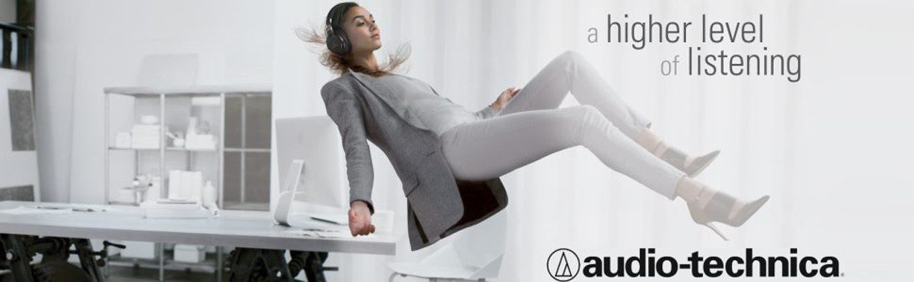 Audio-Technica Banner Showing a Female Office Worker Floating Off Her Desk, Wearing Headphones. There is text that reads: a higher level of listening