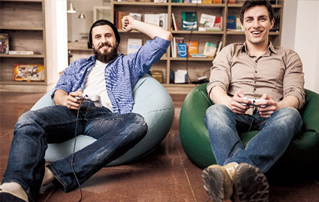A male gamer on a beanbag with wired controller, beard and beanie