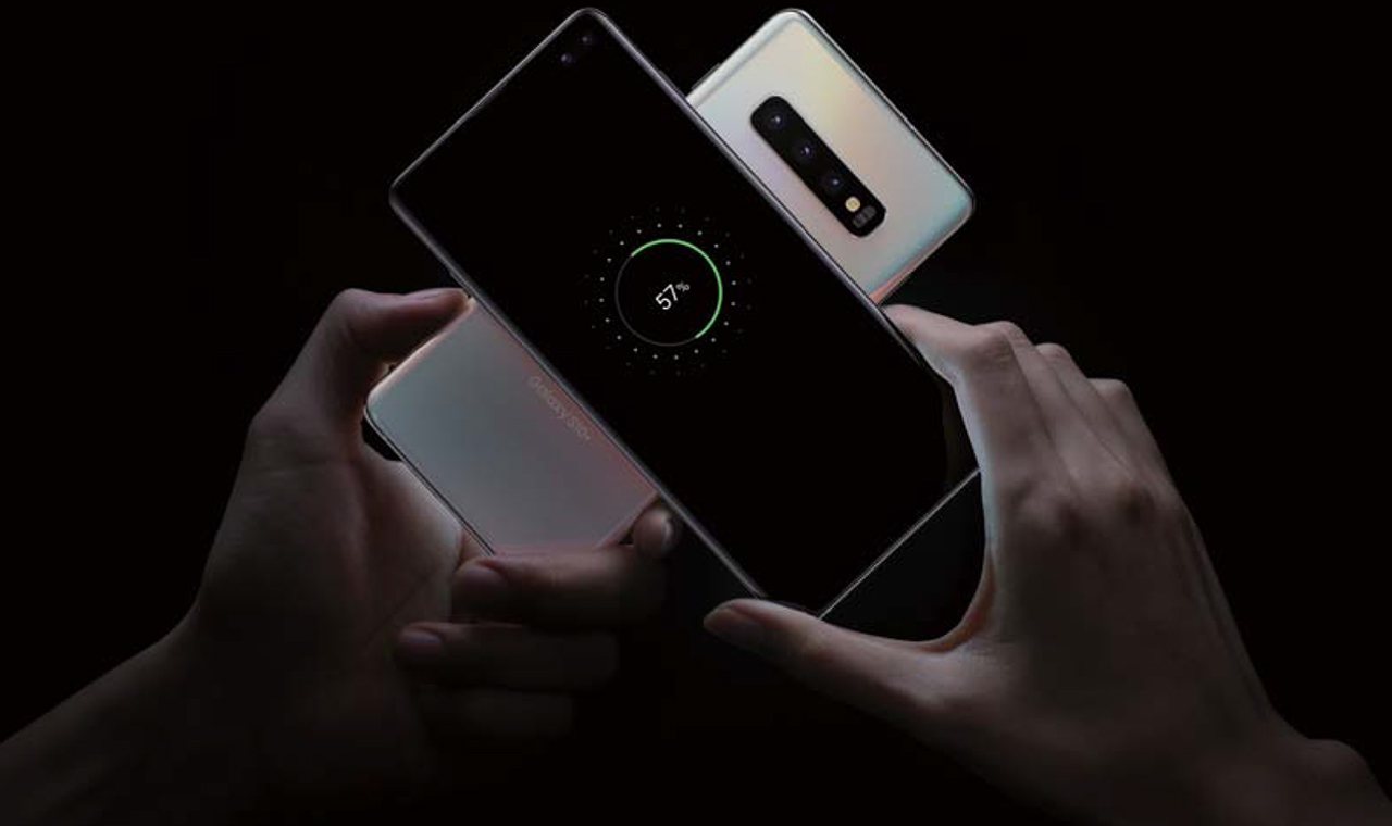 Two Samsung Galaxy S10 phones placed back to back being held by two separate hands