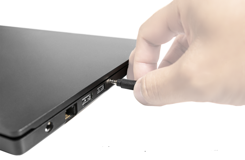 a hand plugging 3.5mm jack into a laptop