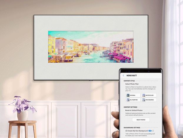 Artwork of a city with canals on a wall-mounted Samsung Q70R display. At the forefront is a hand holding the smartphone that's controlling the image on the TV.