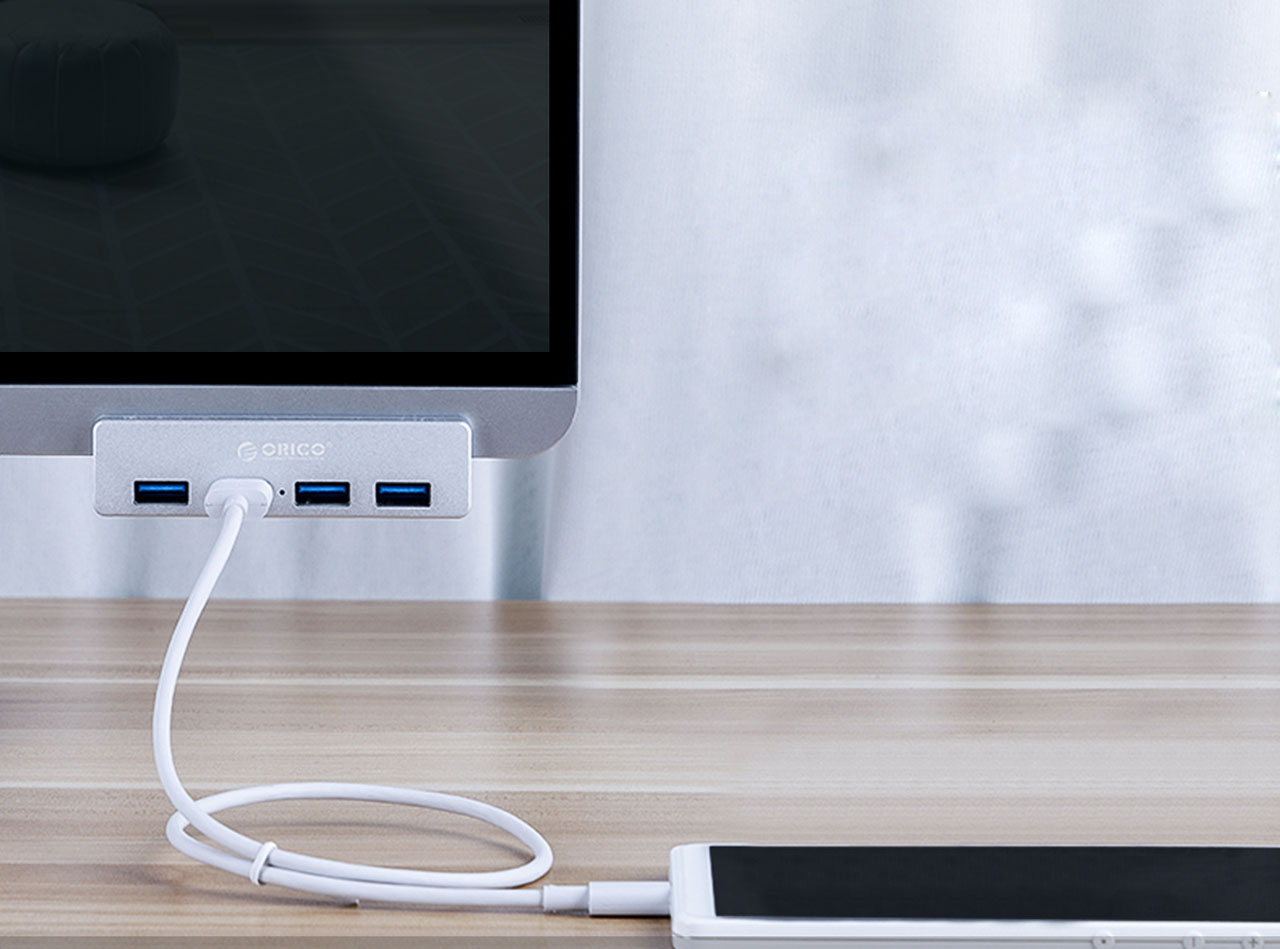 A hub is attached firmly on a montior. A smart phone is connected to the hub's USB 3.0 port via a cable.