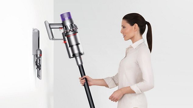 a woman putting Dyson Cyclone V10 to the docking station