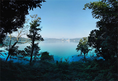 A morning day image of a light blue body of water in between forest trees