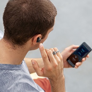  A young male operating phone in his hand, with Liberty Neo earbuds in his ear  
