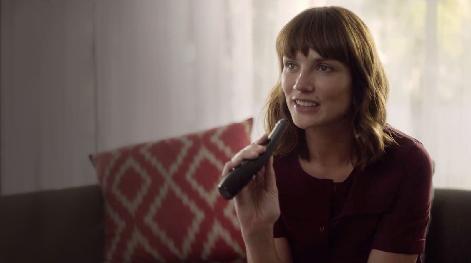 a smiling woman control LG 82UM8070PUA smart TV via the LG Magic Remote