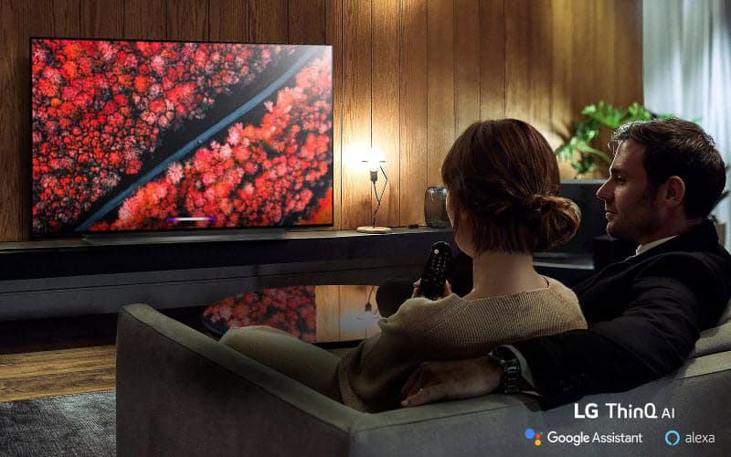 a man and a woman sitting on the sofa are watching LG B9 Smart OLED TV