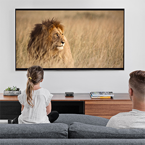 a girl and his father is watching TV showing a lion
