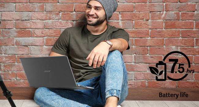 A man sitting with his back to a brick wall and the open Acer Aspire 5 laptop in his lap
