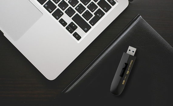 Team Group USB Drive on a Leather-Covered Notebook Next to a Laptop Keyboard