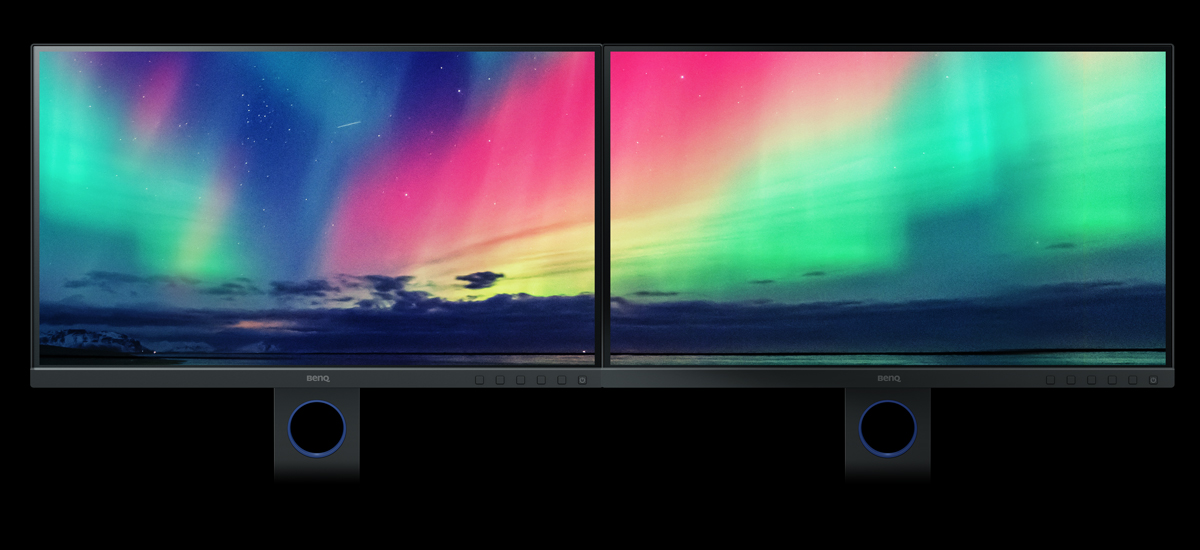 Two BenQ SW270C monitors sharing an image of aurora borealis in the sky