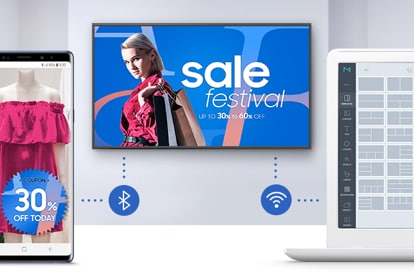 Samsung Display showing a women's clothing and accessories sale ad on a white wall. In the forefront is a smartphone connecting to the display via bluetooth. To the right another device is connecting to the display via WiFi