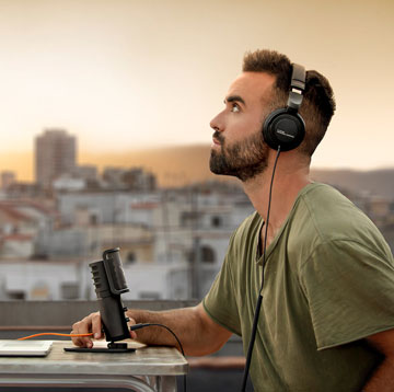 A man on a rooftop in front of the beyerdynamic mic, wearing headphones from the bundle