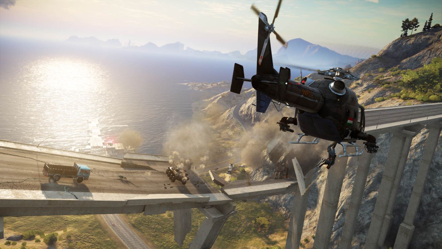 Just Cause 3 Screenshot Showing a Concrete Bridge Breaking Next to the Ocean, and a Helicopter Flying Over