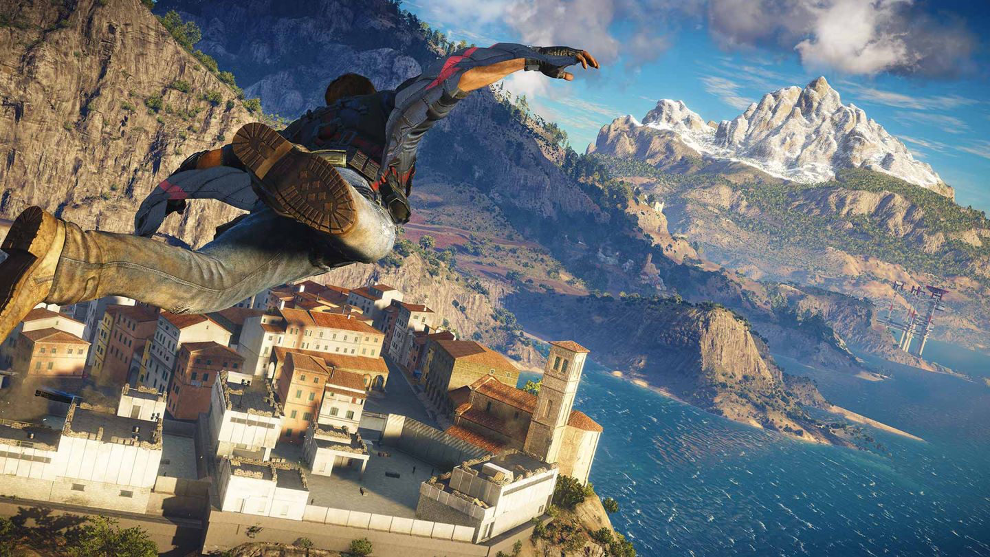 Just Cause 3 Screenshot Showing the Main Character Wingsuit Gliding Towards a Complex by the Ocean