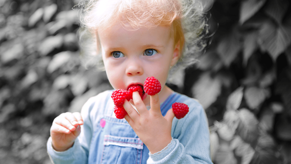 A girl has a red berry on each of her fingers with black background