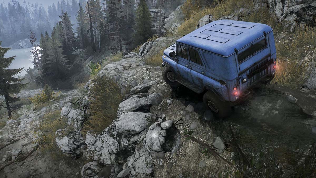 A blue jeep overlooking a wooded area next to a river