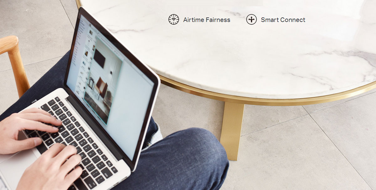 A laptop in someone's lap sitting on a wooden chair next to a marble-top table