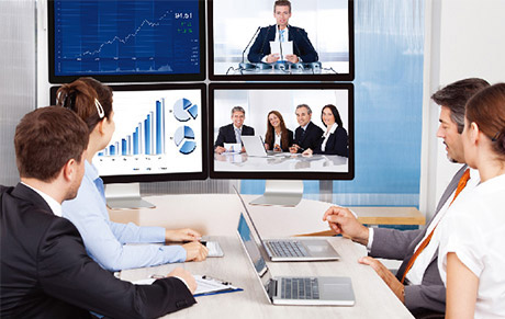 Office workers in a meeting room with multiple displays