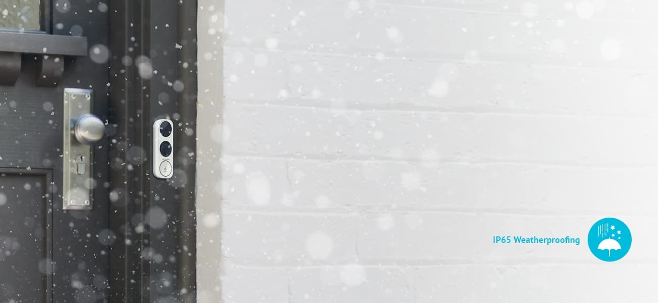 La View Doorbell Surveillance Camera installed next to a door as snow falls in front of it