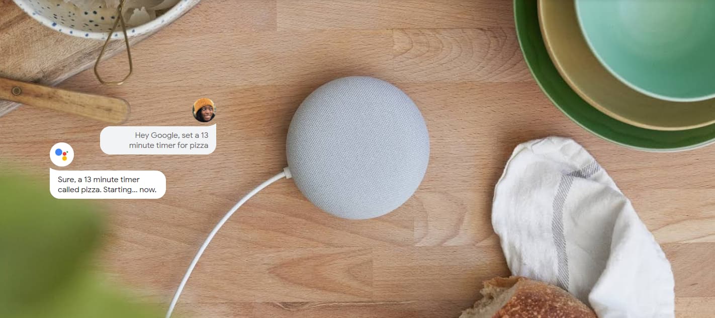 Google Nest Mini placed on a wooden desk alongside some dishes