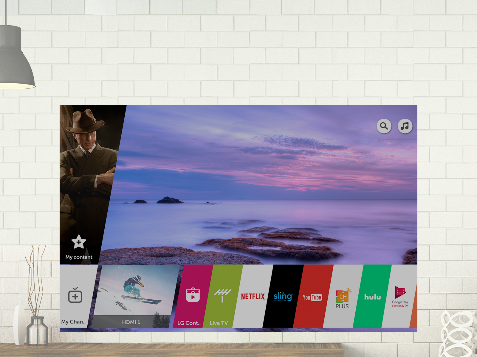 The mounted LG display with a background image of misty covered rocks by the ocean and apps on the bottom of the screen