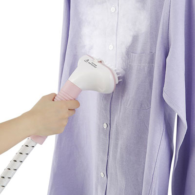  A steamer held in a hand steaming a shirt  