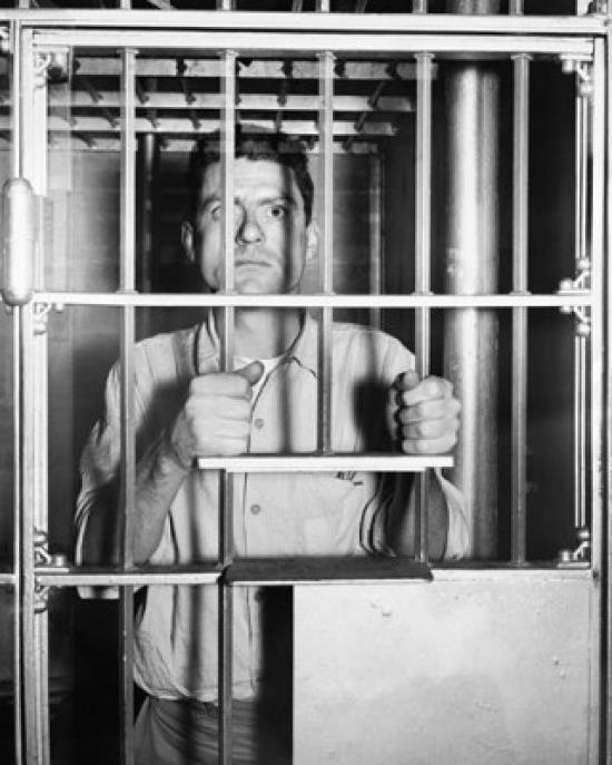 Portrait of a mid adult man standing behind prison bars Poster Print (18 x 24)