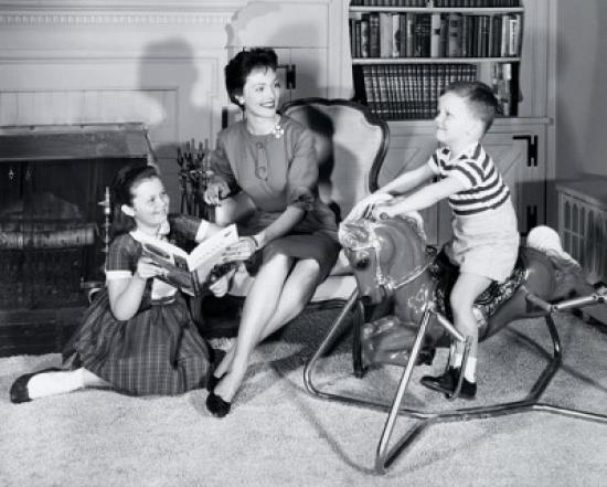 Side profile of a boy sitting on a rocking horse with his mother and sister sitting beside him Poster Print (18 x 24)